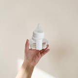 Hand holding a Spectra bottle of expressed breast milk